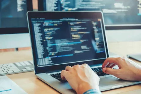 A person working on a laptop, focused on typing and using a computer, representing remote work, freelancing, or digital office tasks.