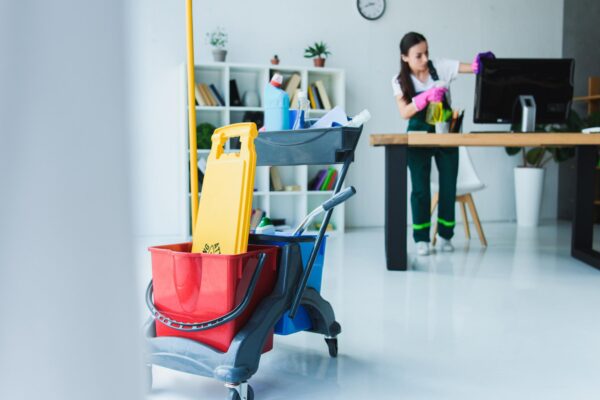 Janitorial Cleaning Services professional cleaning an office workspace with cleaning cart and supplies