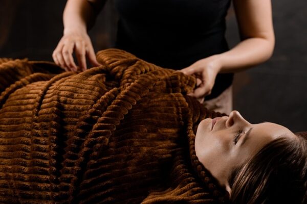 Postpartum Massage Vienna VA providing gentle relaxation therapy for a mother resting comfortably under a warm blanket