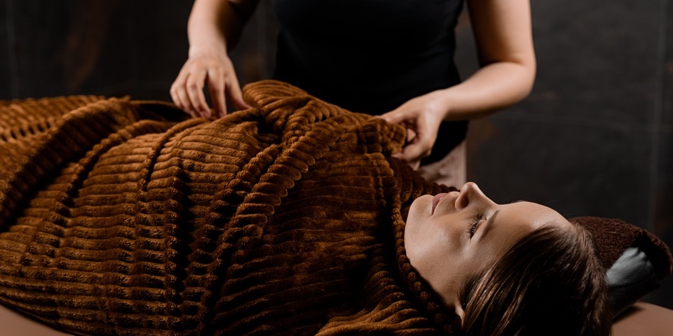 Postpartum Massage Vienna VA providing gentle relaxation therapy for a mother resting comfortably under a warm blanket