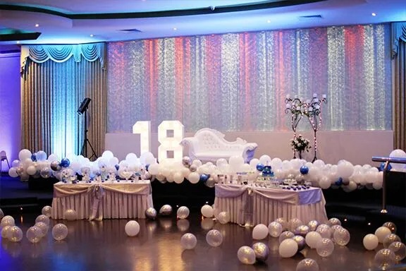 18th birthday party venue setup with white lounge, balloon décor and illuminated number display